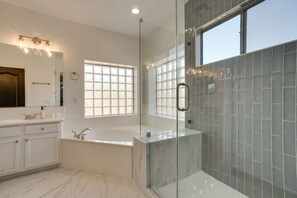 A modern bathroom with a glass-enclosed shower, a freestanding bathtub, and a vanity with a mirror.