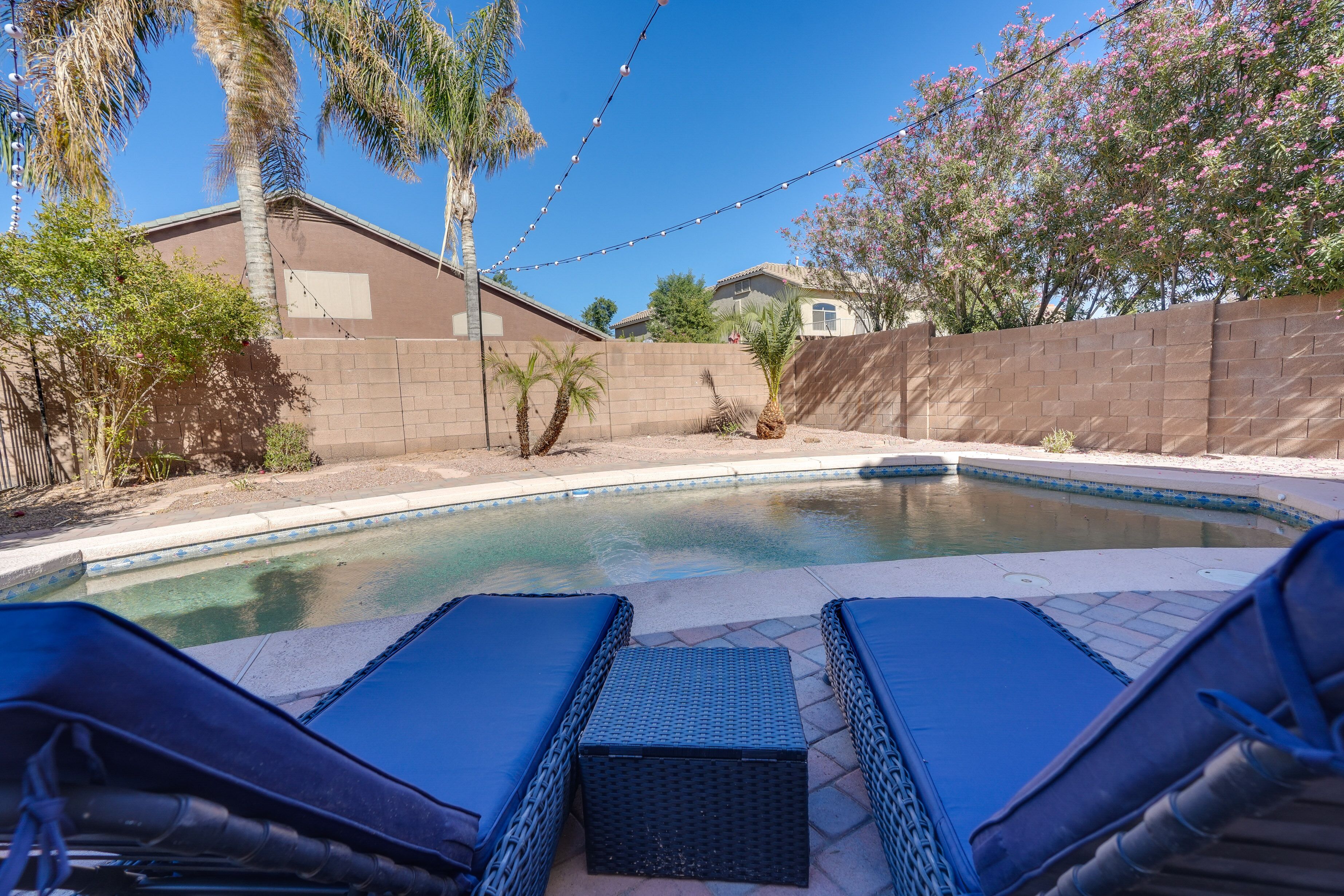 A swimming pool with lounge chairs and a brick wall.