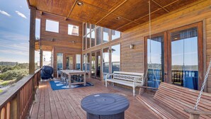 Een houten terras met een tafel, bank en hangstoel.