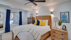 A bedroom with a bed, a wooden headboard, a nightstand with a lamp, a clock, and a framed picture on the wall. - Brian Head Condo w/ Balcony, Grill & Mountain View (Brian Head)