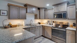 A modern kitchen with granite countertops, stainless steel appliances, and wooden cabinetry. - Brian Head Condo w/ Balcony, Grill & Mountain View (Brian Head)