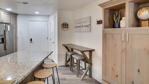 A kitchen with a granite countertop, wooden stools, and a wooden table. - Brian Head Condo w/ Balcony, Grill & Mountain View (Brian Head)