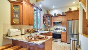 A kitchen with wooden cabinets, a stainless steel refrigerator, a microwave, and a sink. There are wooden stools and a fruit bowl on the counter. - Ski & Golf: Cozy North Conway Mountain Cabin! (North Conway)