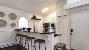 Una cocina moderna con barra, armarios blancos y un refrigerador de acero inoxidable.