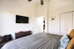 Quarto com cama, penteadeira, televisão de tela plana e armário.
