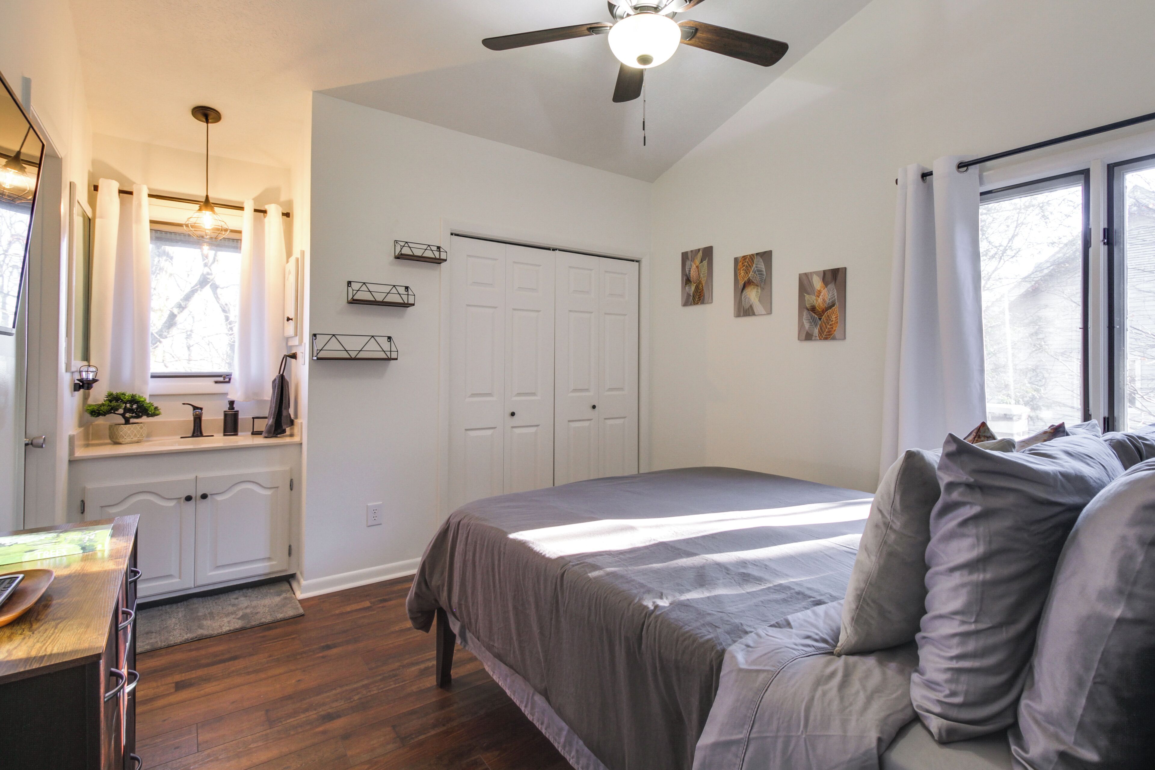 A bedroom with a bed, a ceiling fan, a window, and a door.