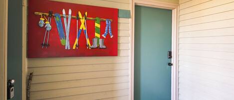 A door with a blue mat and a colorful wall art of skis and snowboards.
