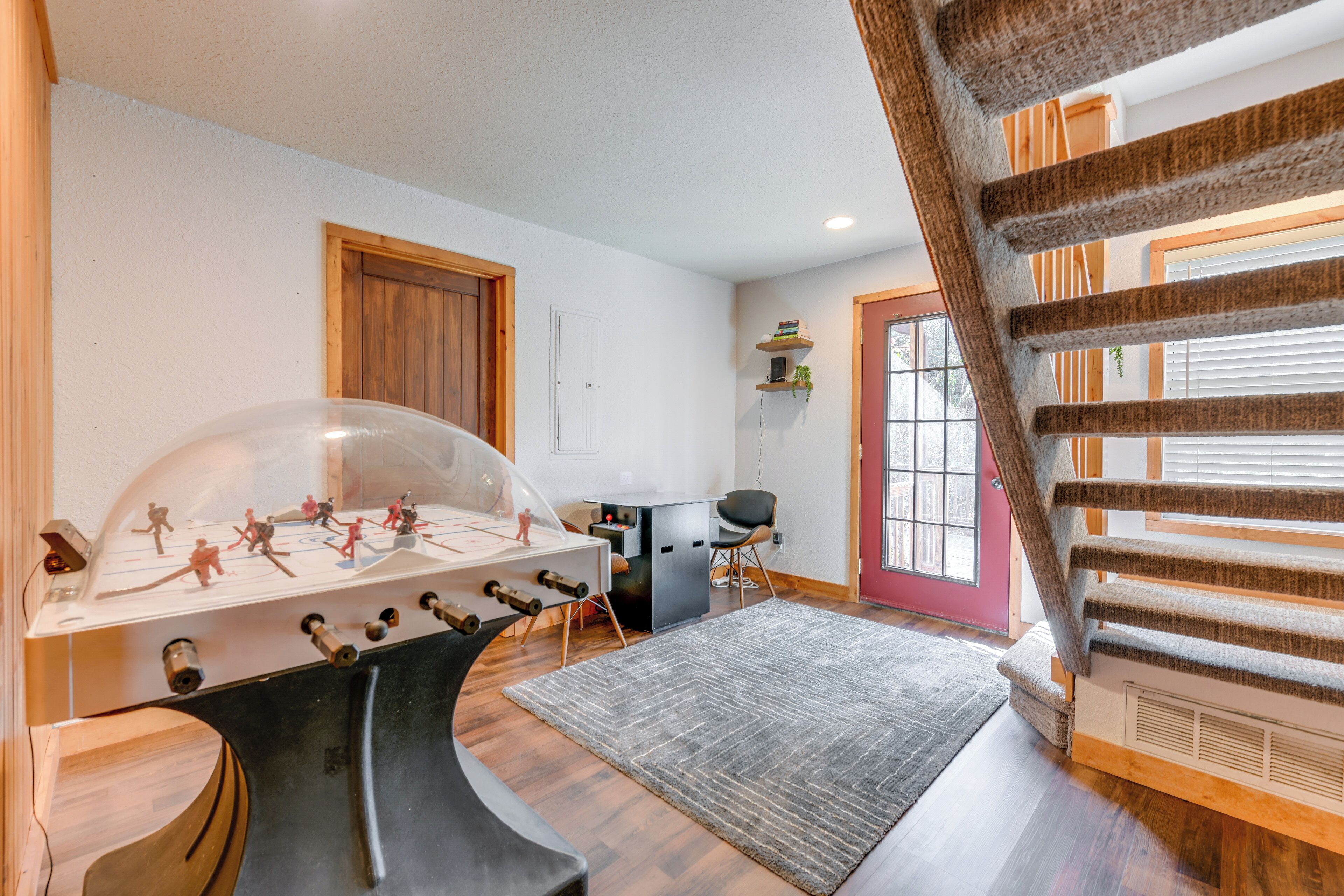 A room with a foosball table, a desk, a chair, and a staircase.