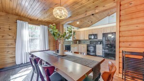 A wooden interior with a dining table, chairs, a chandelier, and kitchen cabinets. - Mtn-view Waynesville Home Near Trout Stocked Creek (Waynesville)