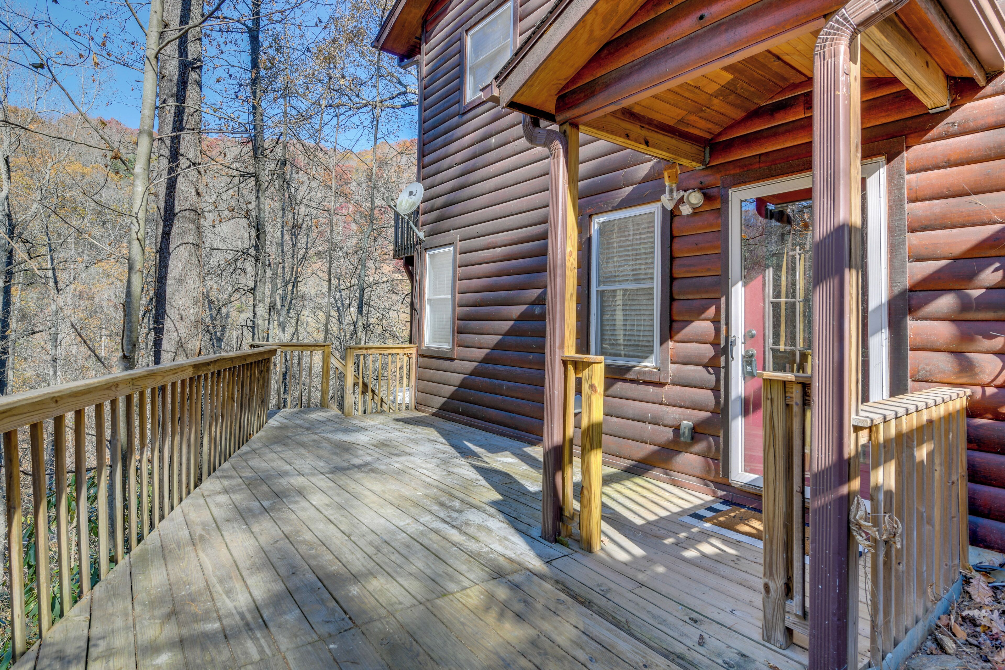 A wooden deck leading to a cabin with a porch, a window, and a door.