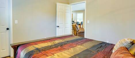 A bedroom with a large bed, a chair, and a door leading to another room.