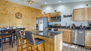 Eine moderne Küche mit Holzschränken, einer zentralen Kochinsel, Barhocker und einer Uhr an der Wand.