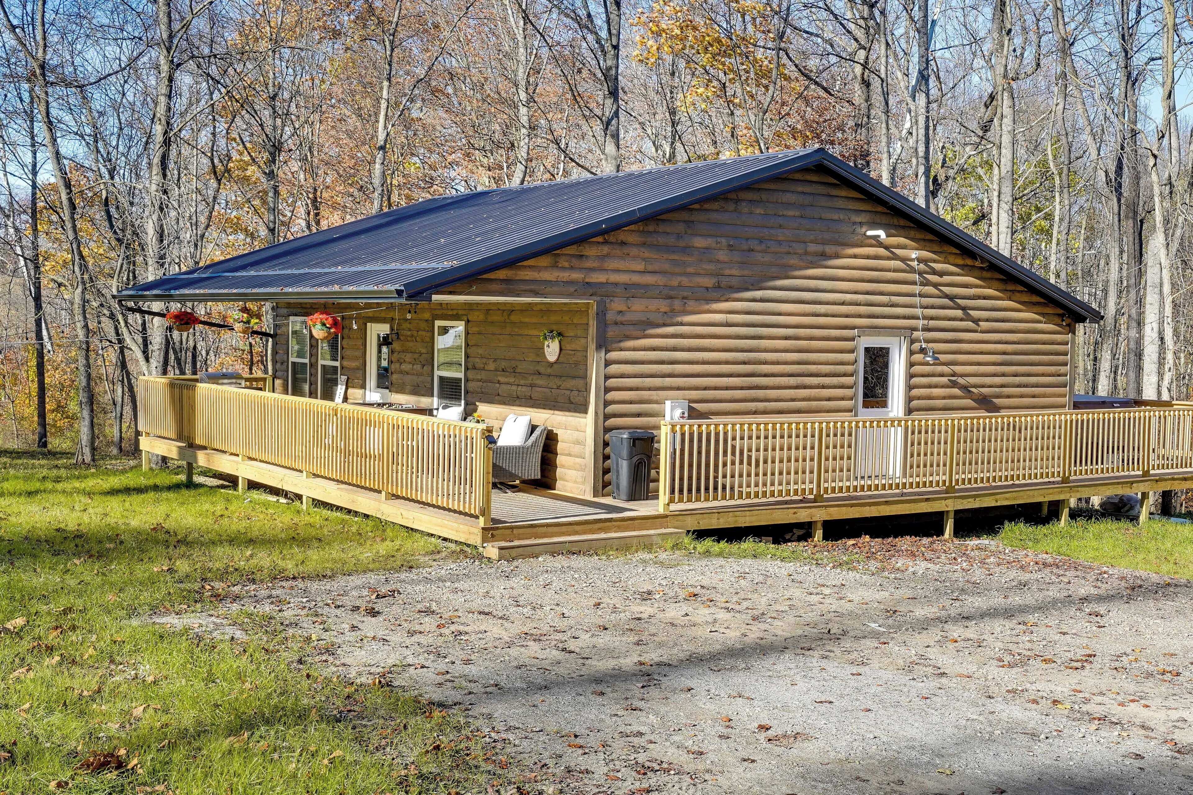 Une cabane en rondins avec un porche, une terrasse couverte et une allée en gravier.