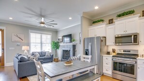 A modern kitchen with white cabinetry, stainless steel appliances, and a dining area with a wooden table and benches. - Lake Access & Boat Slip: Greenwood Cottage! (Greenwood)