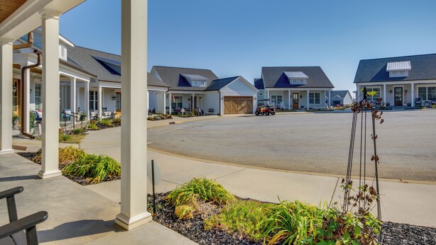 A row of single-story houses with a covered porch area, a paved driveway, and a clear blue sky. - Lake Access & Boat Slip: Greenwood Cottage! (Greenwood)