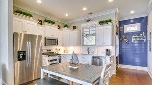 A modern kitchen with white cabinetry, stainless steel appliances, and a wooden dining table. - Lake Access & Boat Slip: Greenwood Cottage! (Greenwood)