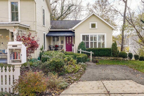 Une maison à deux étages avec un porche à l’avant, une boîte aux lettres et un jardin bien entretenu.