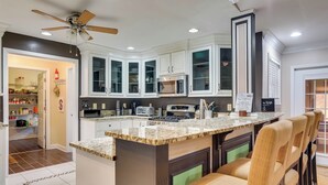 A modern kitchen with a central island, built-in cabinets, and a ceiling fan. - Moncks Corner Home ~ 4 Mi to Lake Moultrie! (Moncks Corner)