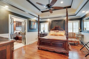 A spacious bedroom with a four-poster bed, a ceiling fan, and a view of the kitchen through an open door. - Moncks Corner Home ~ 4 Mi to Lake Moultrie! (Moncks Corner)