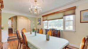 A dining room with a long table, wooden chairs, a chandelier, and a window with blinds. - Moncks Corner Home ~ 4 Mi to Lake Moultrie! (Moncks Corner)