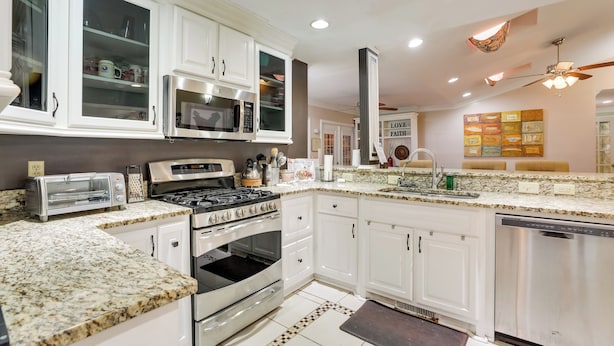 A modern kitchen with white cabinets, stainless steel appliances, granite countertops, and a built-in oven. - Moncks Corner Home ~ 4 Mi to Lake Moultrie! (Moncks Corner)