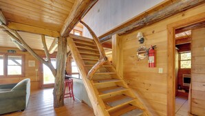 A wooden interior with a spiral staircase, a sofa, and a fire extinguisher on the wall. - Remote Escape: Vermont Cabin w/ Mountaintop Views! (Sharon)