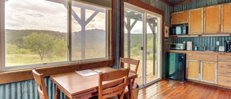 Una cocina rústica con armarios de madera, una mesa de comedor con sillas y un ventanal con vistas al exterior.