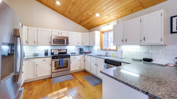 A modern kitchen with white cabinets, a stainless steel refrigerator, a microwave, an oven, and a dishwasher. - Pet-friendly Cabin w/ Fire Pit in Spruce Pine! (Spruce Pine)