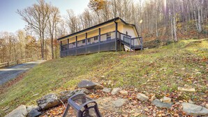 A cabin with a porch, surrounded by a forested area with fallen leaves. - Pet-friendly Cabin w/ Fire Pit in Spruce Pine! (Spruce Pine)
