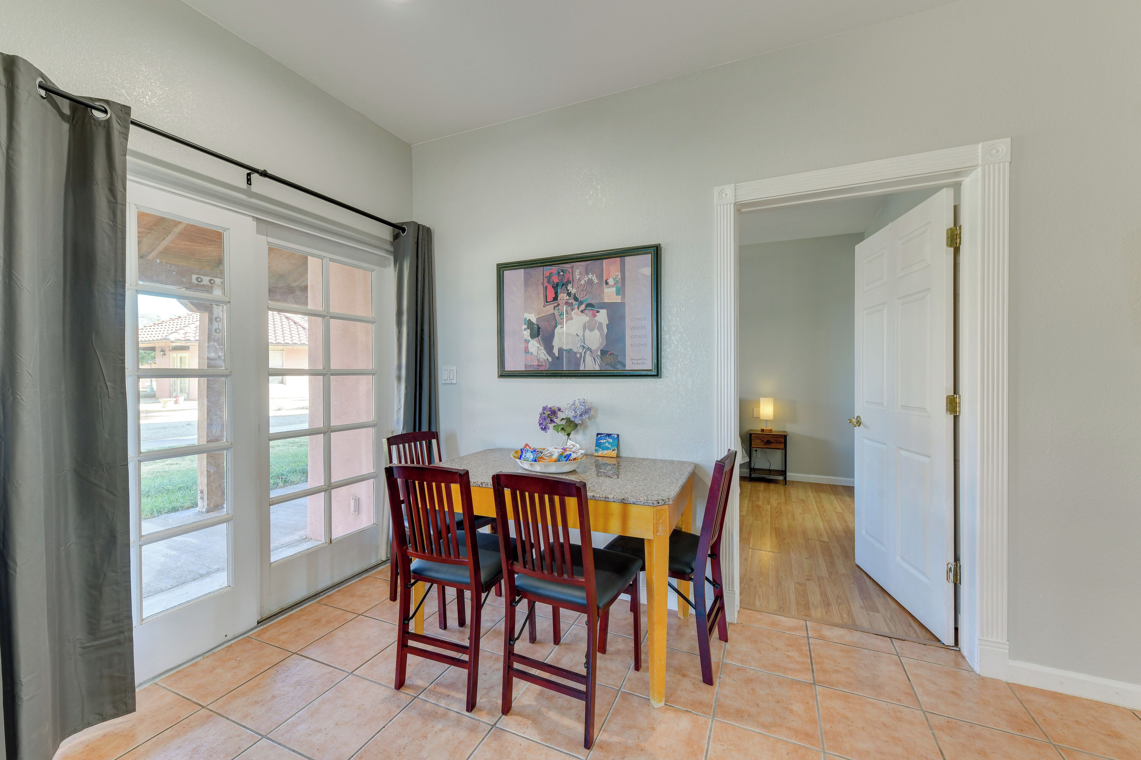 A dining area with a table, chairs, a framed picture, and a door leading to another room.
