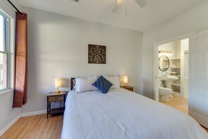 A bedroom with a large bed, a nightstand with a lamp, a wall-mounted artwork, and a view into the bathroom. - Eloy Vacation Rental w/ Community Pool & Courtyard (Eloy)