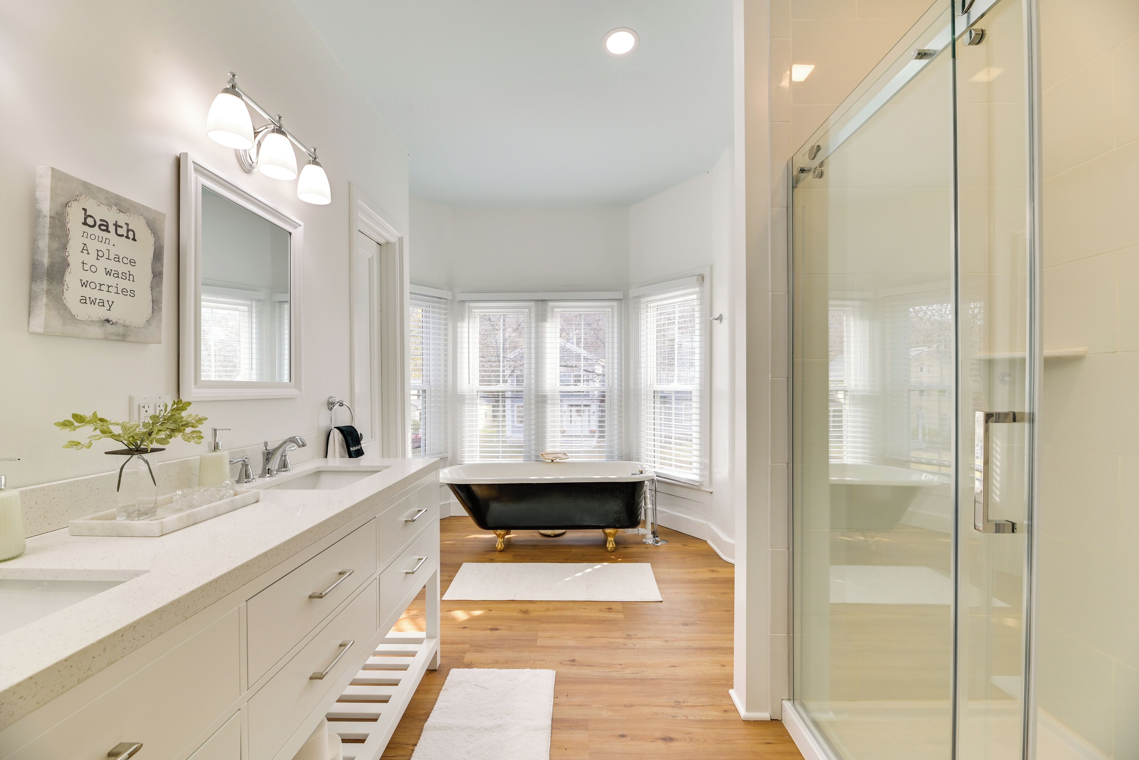 A modern bathroom with a freestanding bathtub, a glass shower enclosure, and a vanity with a mirror and lights.