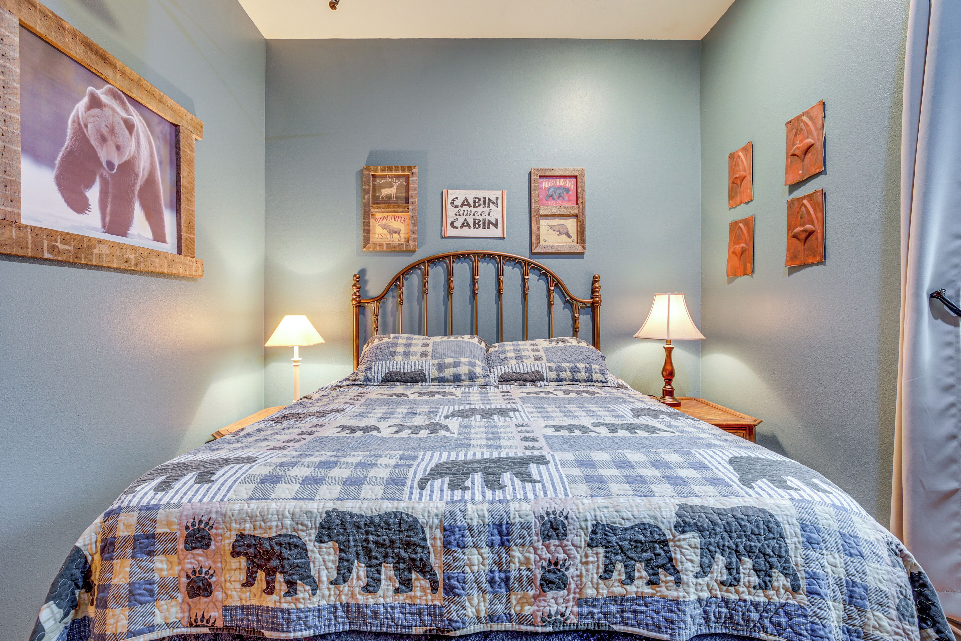 A bedroom with a bed, two bedside tables, a wall-mounted lamp, and framed pictures.
