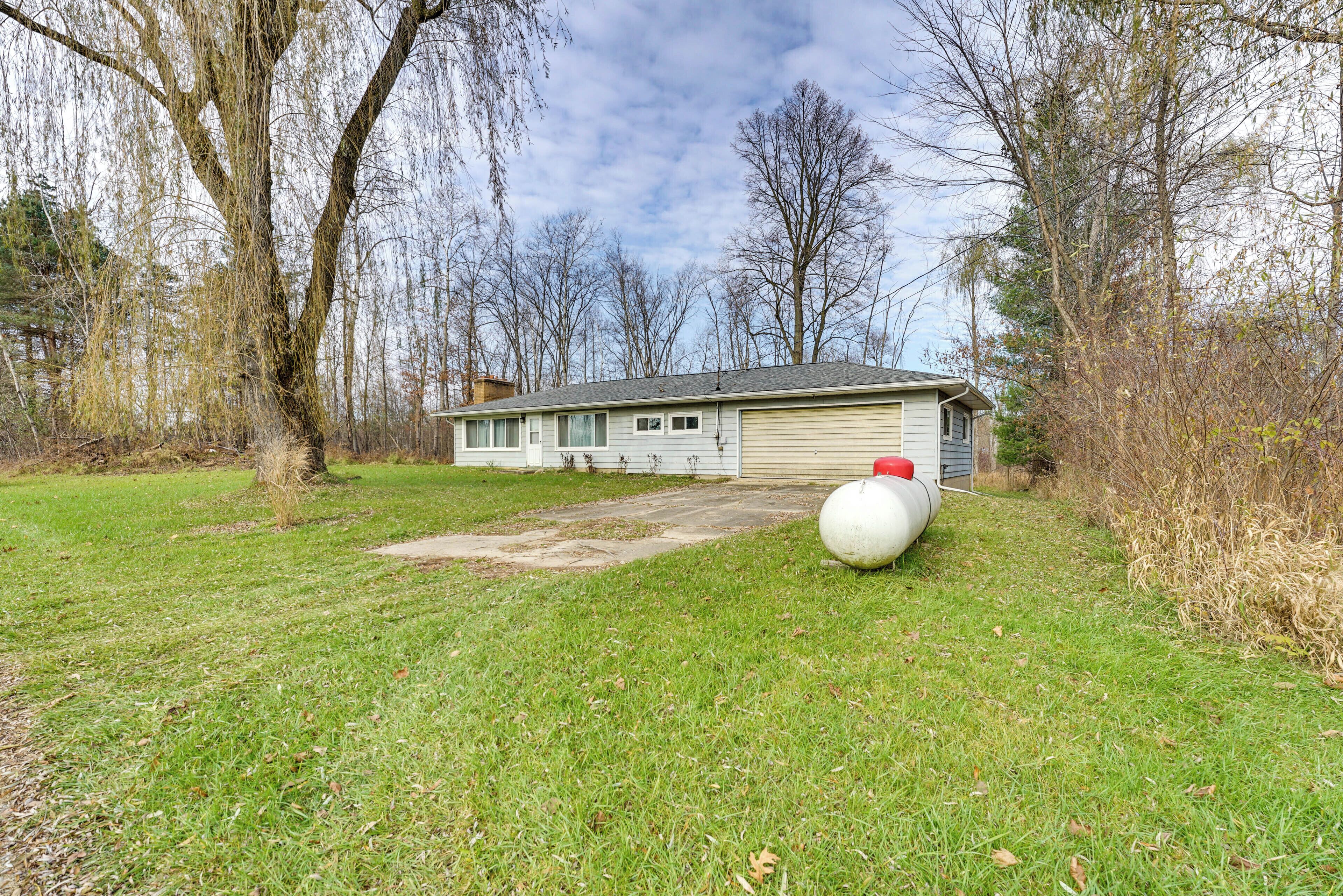 Een gelijkvloers huis met garage, omgeven door een gazon en bomen.