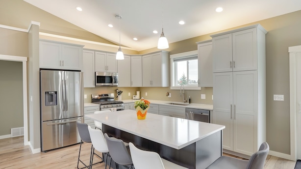 A modern kitchen with a central island, stainless steel appliances, and white cabinetry.