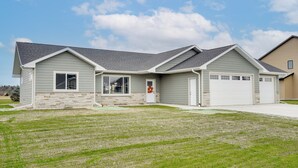 A two-story house with a stone foundation, a garage, and a well-maintained lawn.