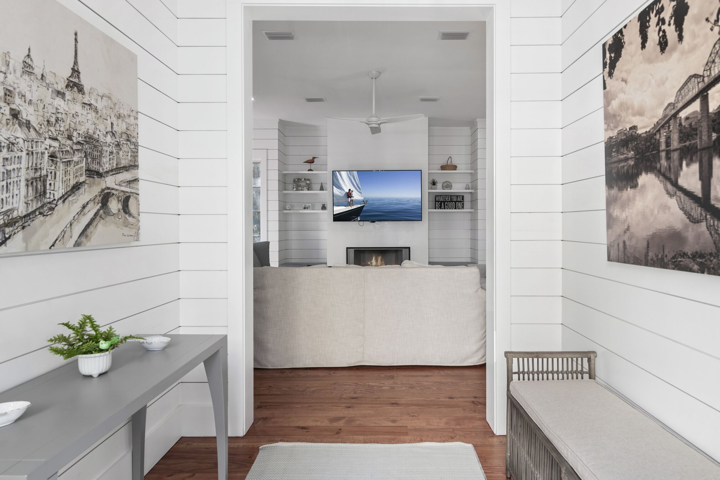 Una cucina moderna con una grande TV, mobili bianchi e vista mare.