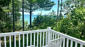 A white wooden deck with a bench, overlooking a forested area with a view of the ocean. - Beautiful Lake Michigan Home Great for Large (West Olive)
