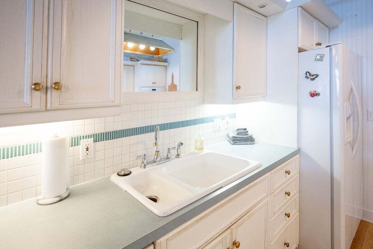 A kitchen with white cabinets, a double sink, and a refrigerator with magnets.