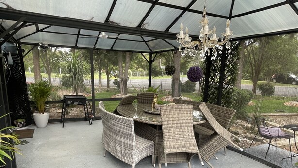 Un patio cubierto con mobiliario de mimbre y un candelabro.