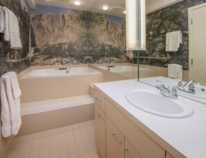 Un baño con dos lavamanos, una bañera y un espejo grande.