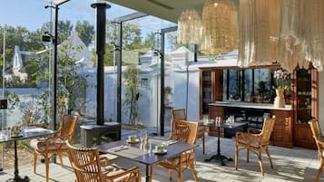An outdoor dining area with wicker furniture, a bar, and hanging lights.