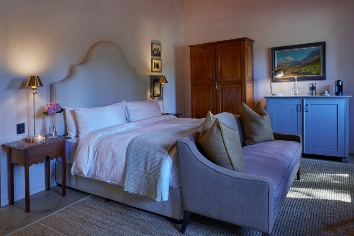 Een slaapkamer met een bed, nachtkastjes, een garderobe en een schilderij aan de muur.