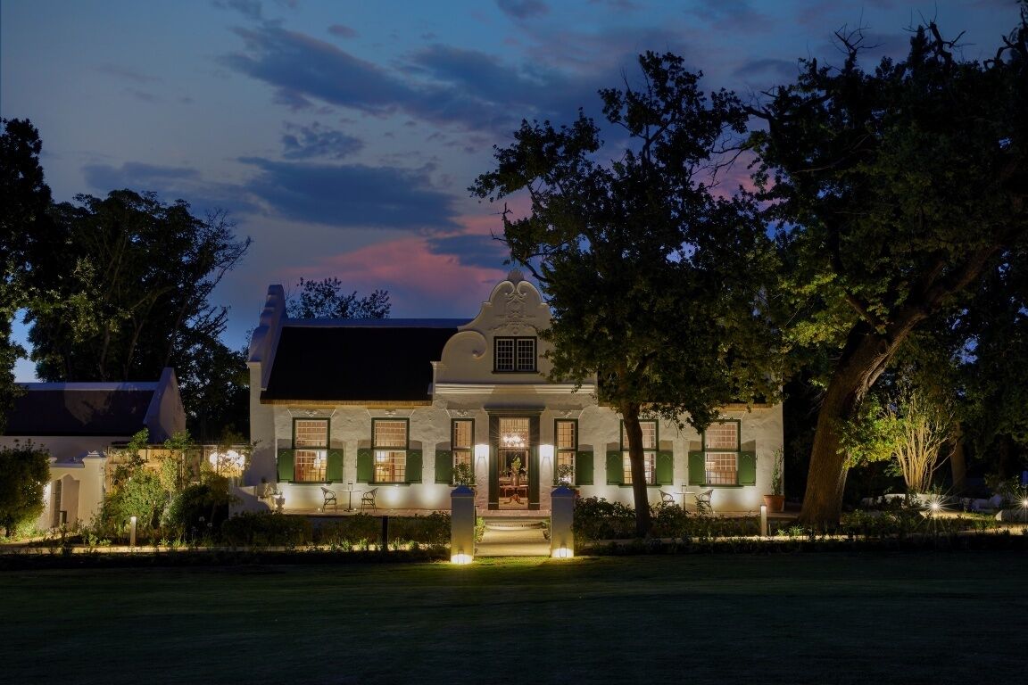 A large, two-story house with a symmetrical facade, a prominent central entrance, and a well-maintained garden.
