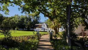 Un sendero que lleva a un edificio blanco con jardín y árboles.