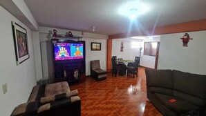 A living room with a television, a sofa, a coffee table, and a dining area with chairs. - Umary Wai ............................. (Cusco)