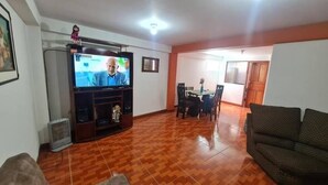 A living room with a television, a sofa, and a dining area with chairs and a table. - Umary Wai ............................. (Cusco)