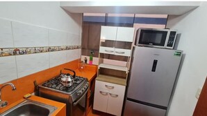 A compact kitchen with a gas stove, a microwave, and a refrigerator. - Umary Wai ............................. (Cusco)