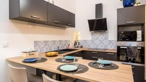 Une cuisine moderne avec des meubles de couleur sombre, un îlot central en bois et un four encastré.