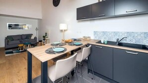 Une cuisine de taille réduite, avec des meubles de couleur sombre, un plan de travail en bois et un revêtement mural en carreaux.